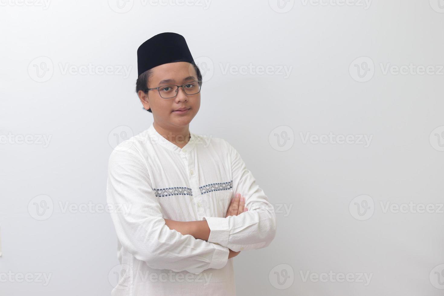 retrato de joven asiático musulmán hombre en pie con cruzado brazos y mirando a cámara. aislado imagen en blanco antecedentes foto
