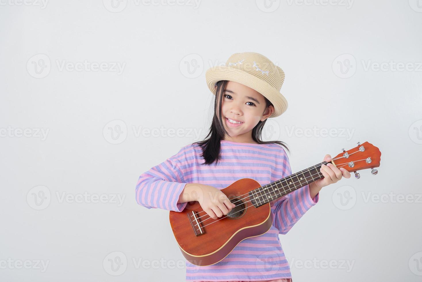 Cute little girl in swimsuit playing ukulele. Happy vacation concept. photo