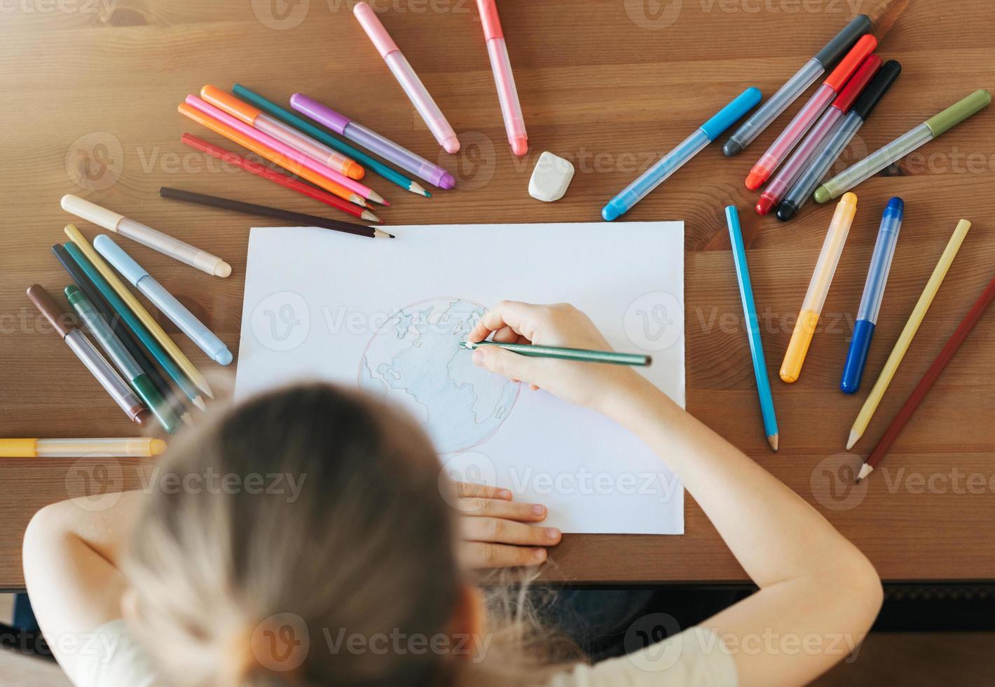 Child girl drawing with colorful pencils photo