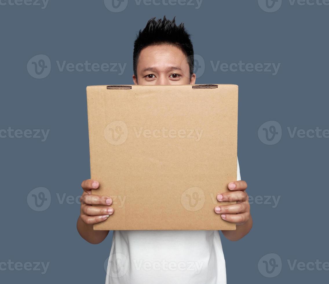 Man covering his face with cardboard box isolated on plain bacground photo