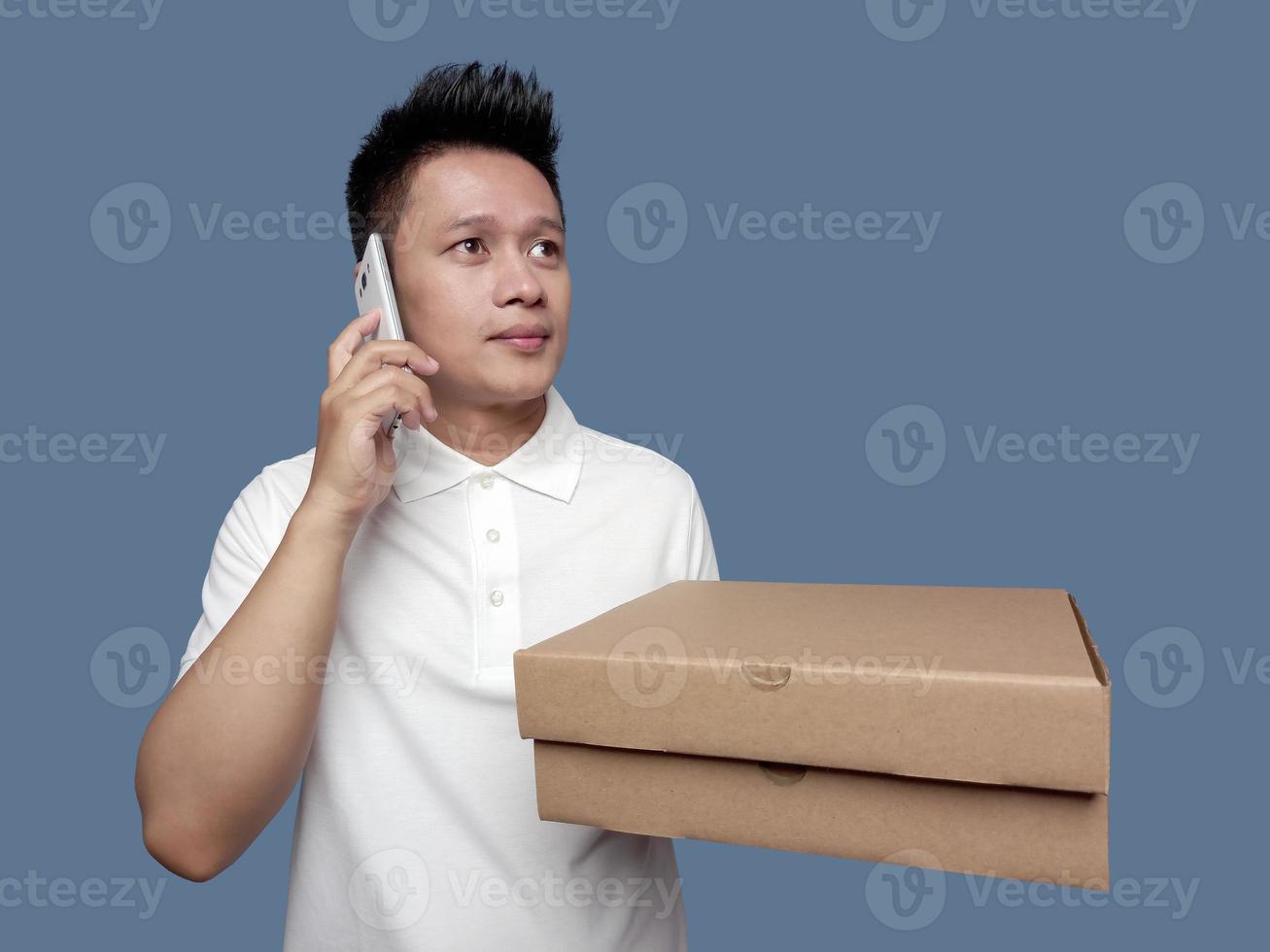 Man holding a cardboard box while making a phone call and looking up. photo
