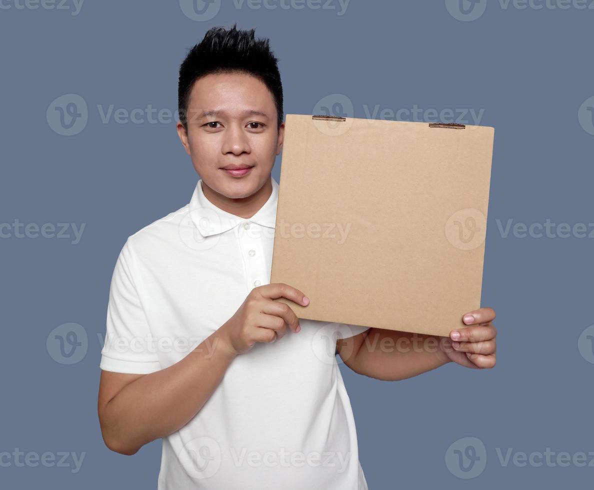 Man holding and showing brown cardboard box isolated on plain background. photo