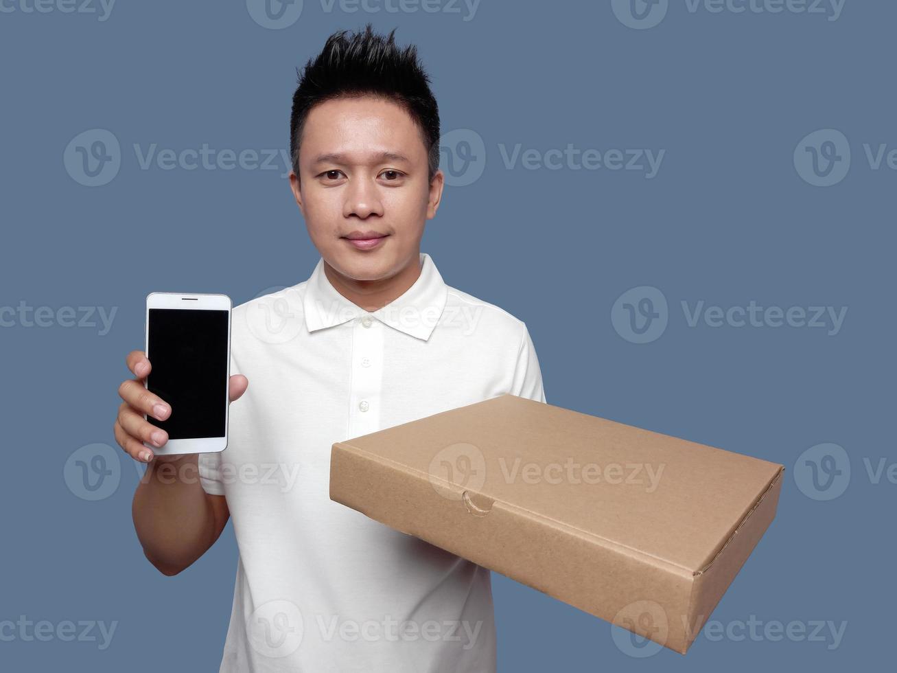 Man wearing collar shirt holding cardboard box and showing smartphone front view photo