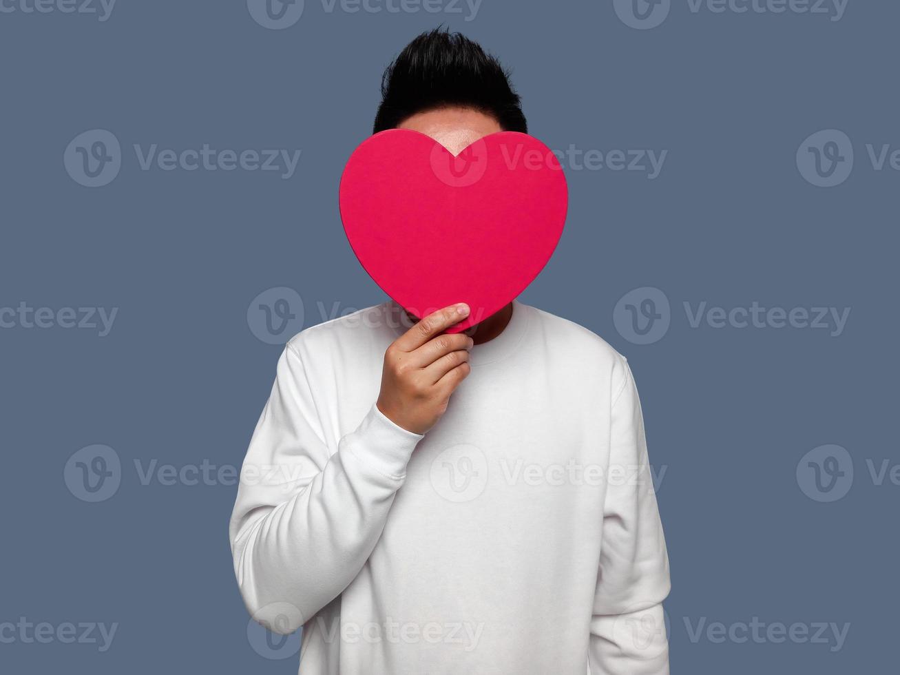 Man covering his face with red heart shape. photo