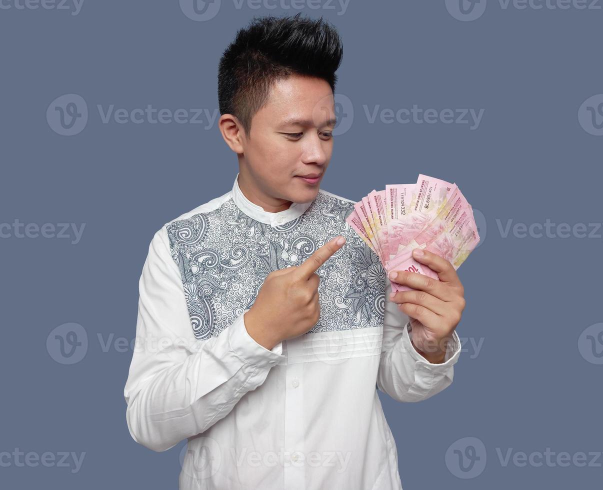 Young man holding and pointing Indonesian money one hundred thousand rupiah photo