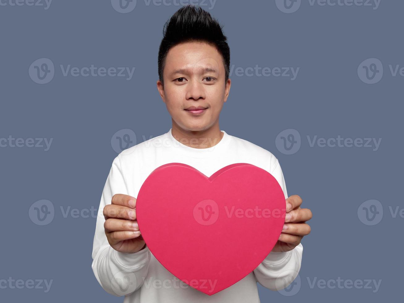 Handsome man holding and showing red heart shape with both hands photo