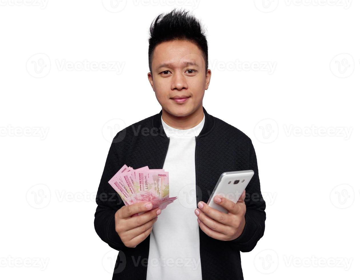 Handsome man holding smartphone and holding indonesian money smiling looking at camera photo