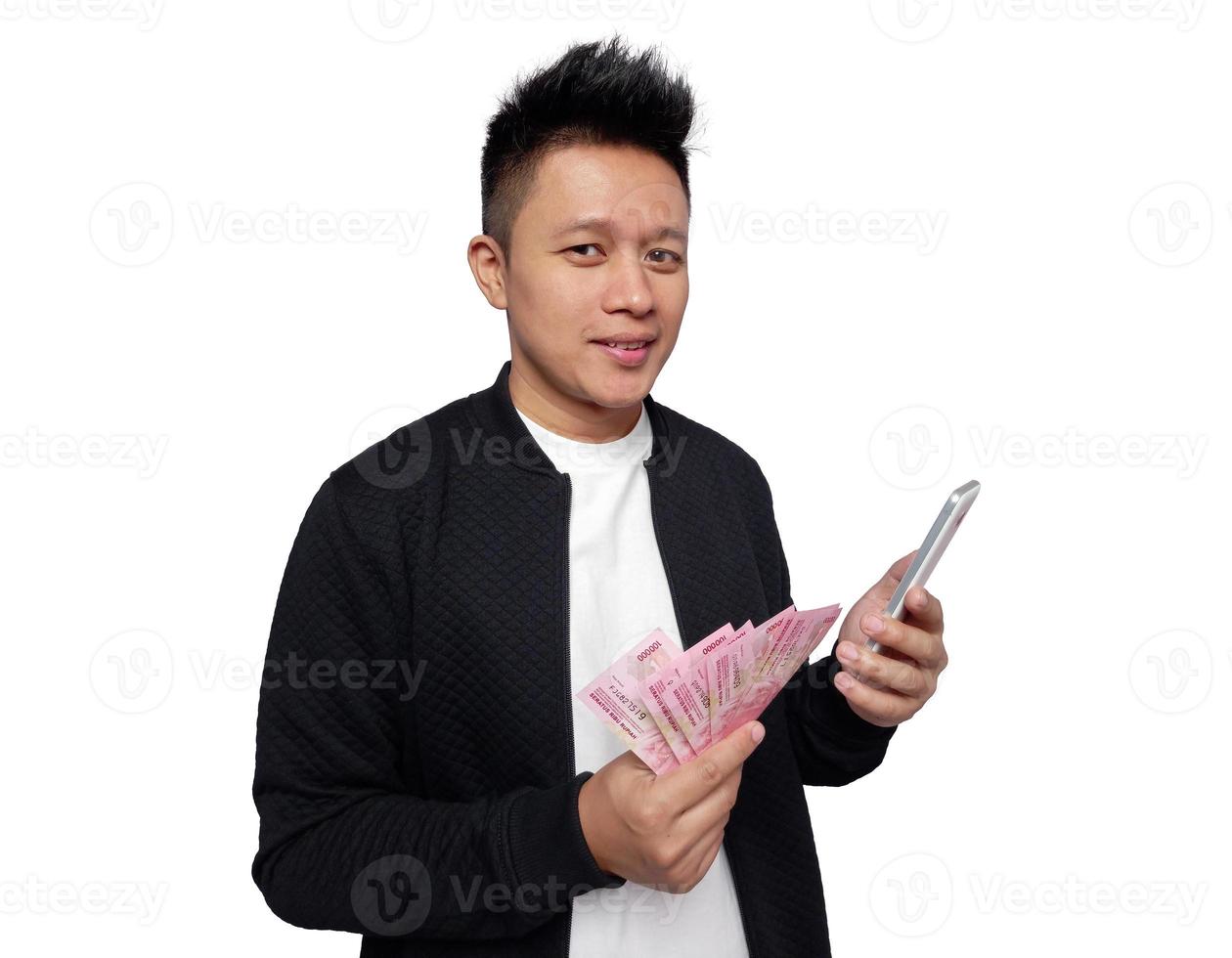 Handsome man holding smartphone and holding indonesian money smiling looking at camera photo