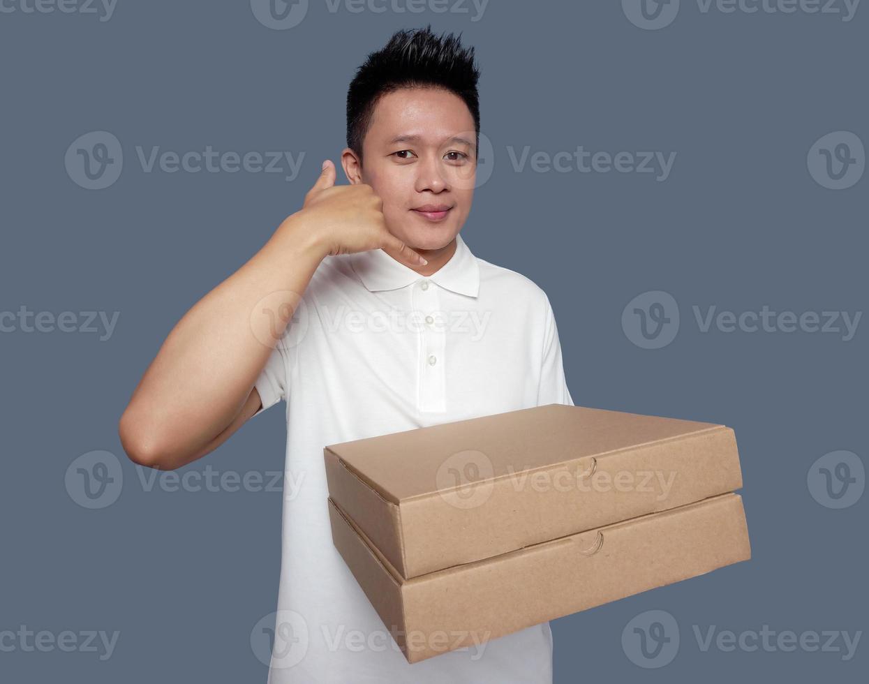 Man holding cardboard box with hand gesture making phone call. photo