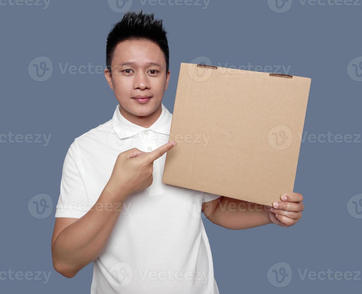 Man holding and pointing at brown cardboard box isolated on plain background. photo