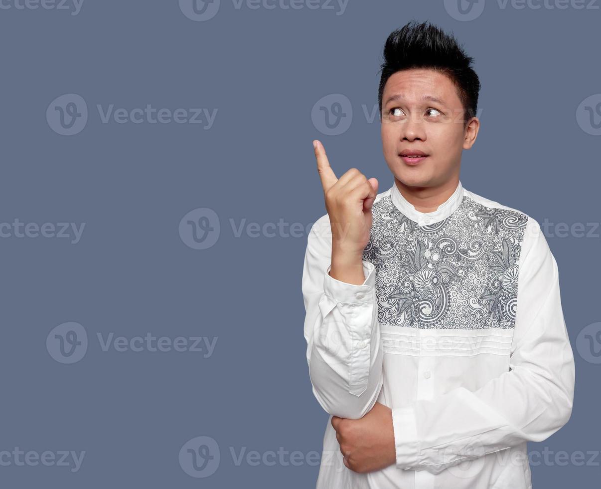 Handsome man in koko shirt is looking up and pointing to the left. photo