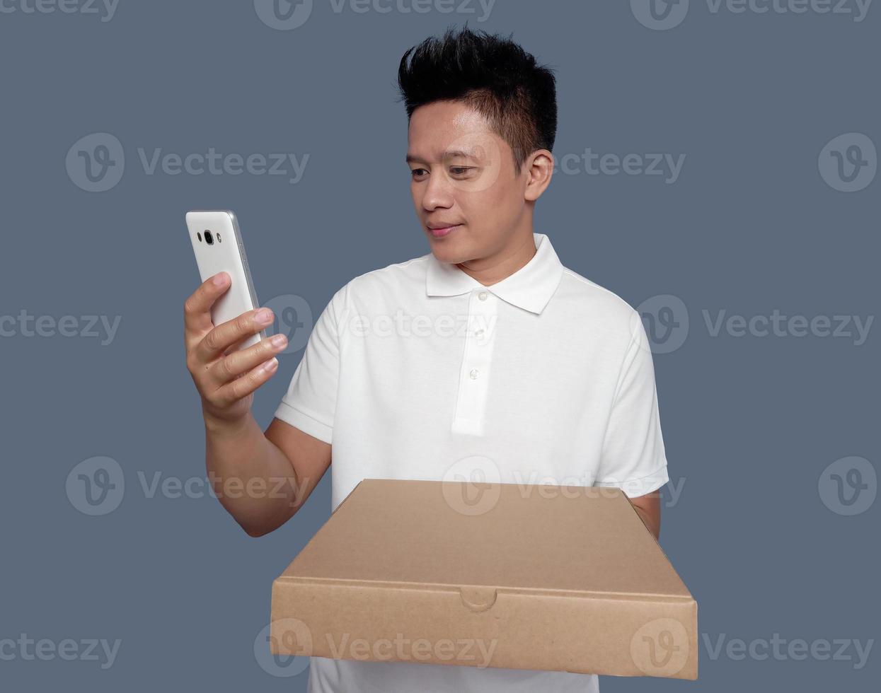 Man looking at cell phone screen holding cardboard box photo