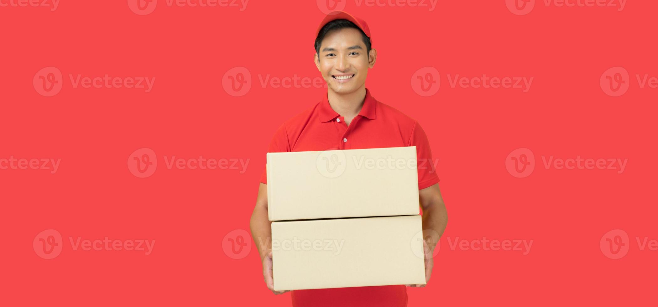 The smiling delivery man is dressed in a red cap and blank t-shirt uniform, and is standing in front of a red background photo