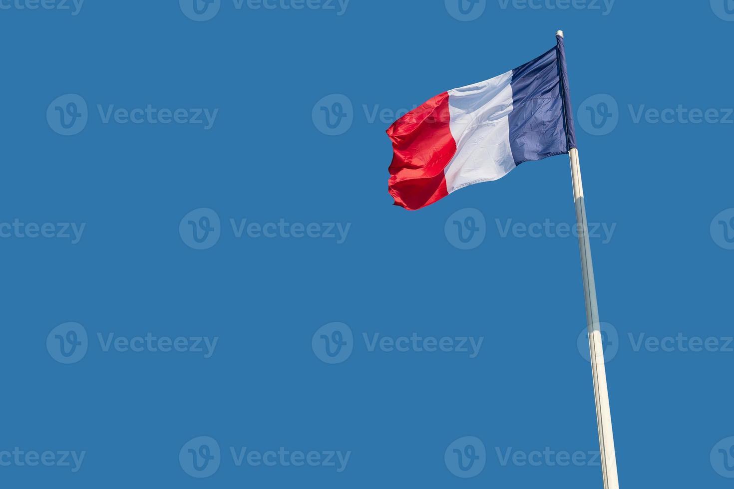 The national flags of France flutter against a blue sky. photo