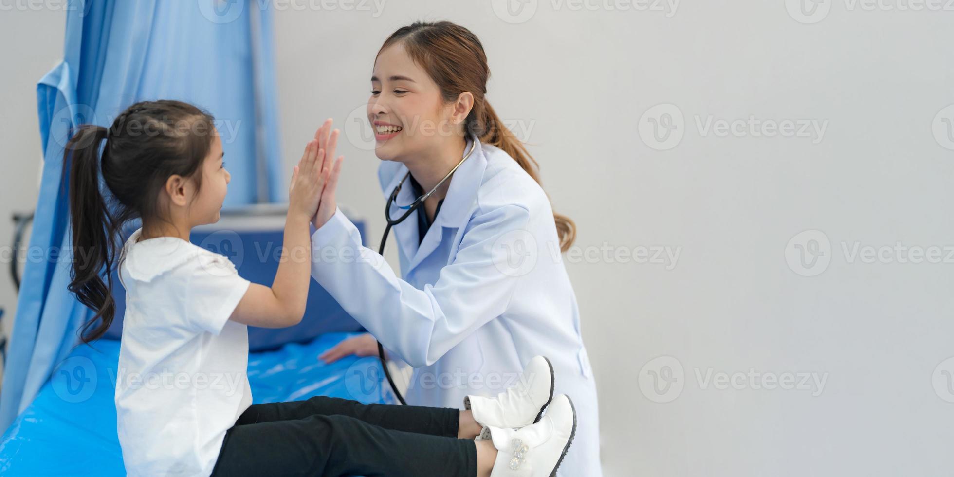 el niña se sienta en el del paciente cama para el doctor. foto