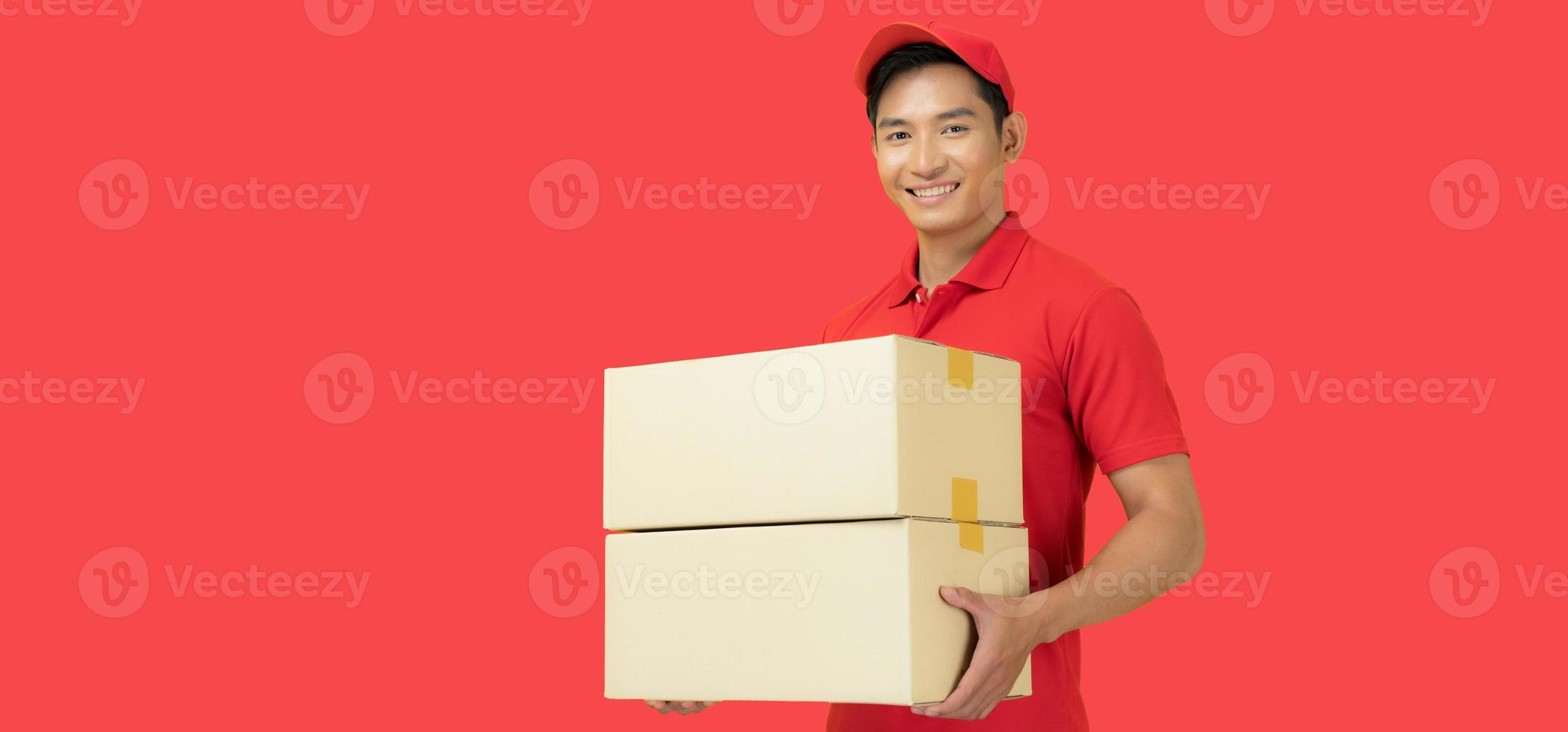 The smiling delivery man is dressed in a red cap and blank t-shirt uniform, and is standing in front of a red background photo
