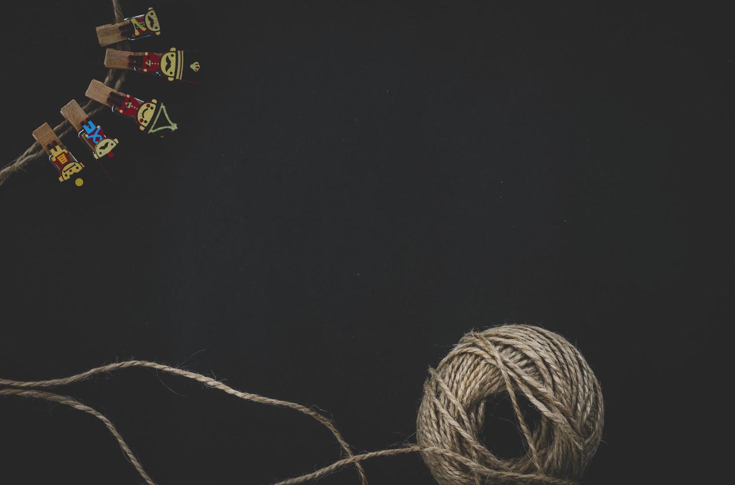 wooden clothespins in soldiers characters and wool yarn isolated on dark background. Top view of copy space photo