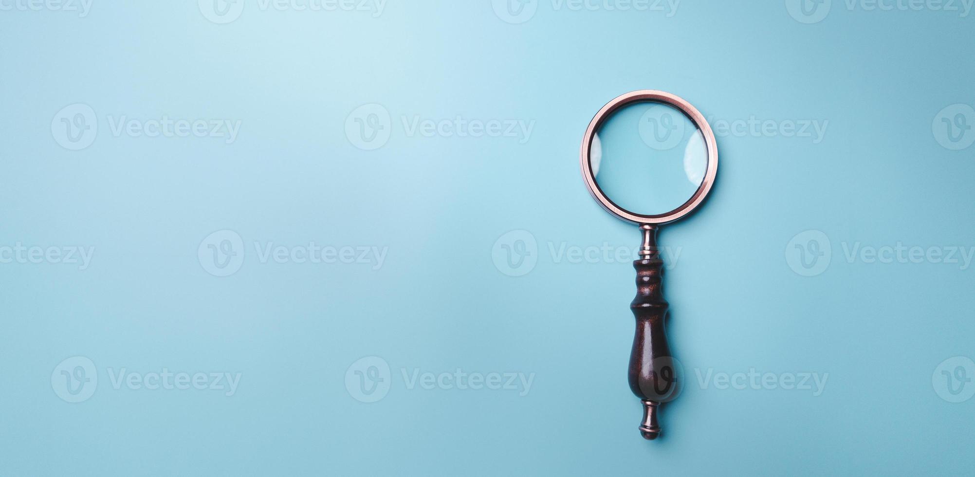 Magnifying glass on blue background. Top view. Flat lay. Copy space. Minimal creative concept. Blue background in pastel colours photo