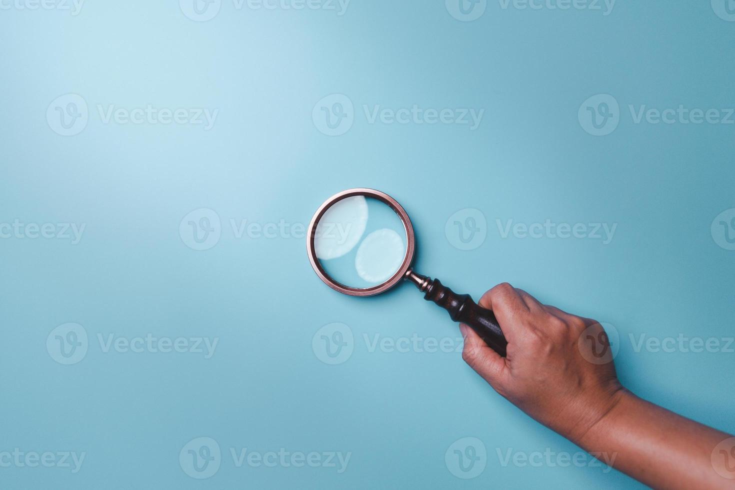 Magnifying glass on blue background. Top view. Flat lay. Copy space. Minimal creative concept. Blue background in pastel colours photo