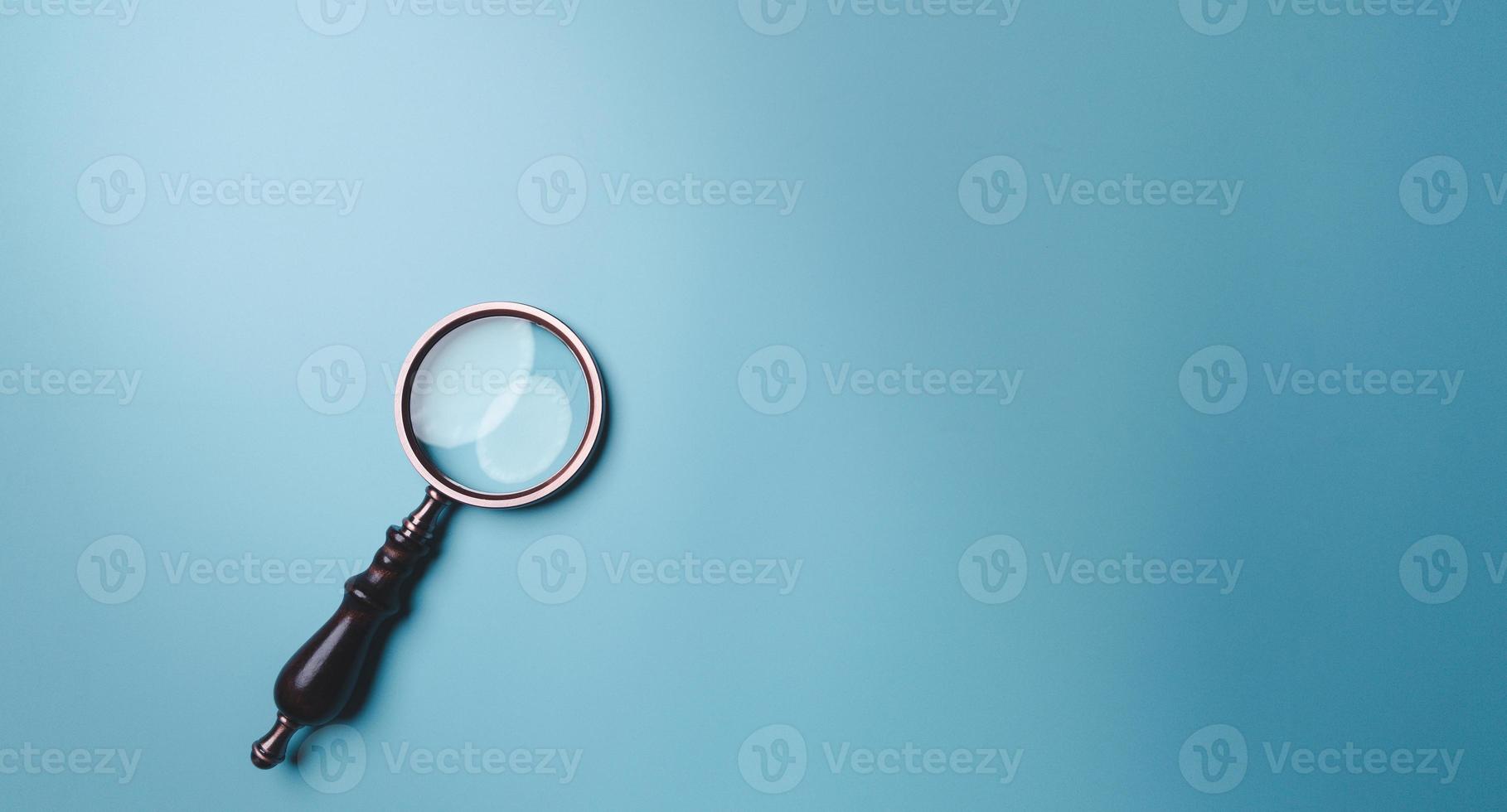 Magnifying glass on blue background. Top view. Flat lay. Copy space. Minimal creative concept. Blue background in pastel colours photo