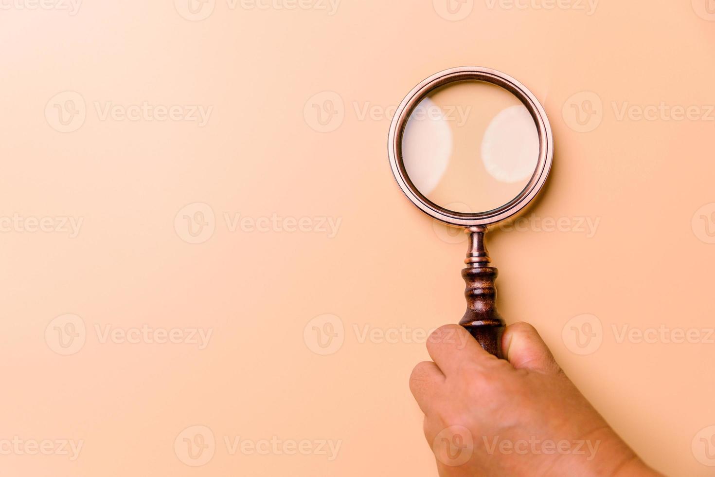 Magnifying glass on orange background. Top view. Flat lay. Copy space. Minimal creative concept. Blue background in pastel colours photo