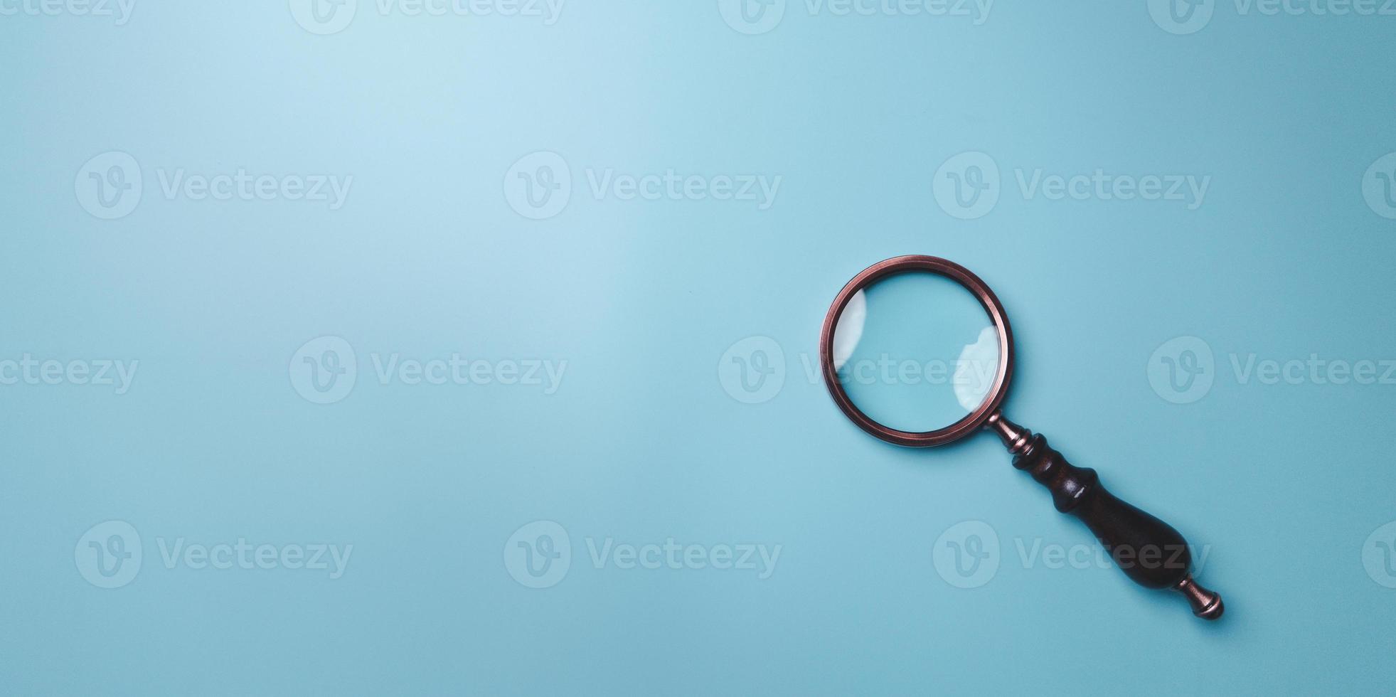 Magnifying glass on blue background. Top view. Flat lay. Copy space. Minimal creative concept. Blue background in pastel colours photo