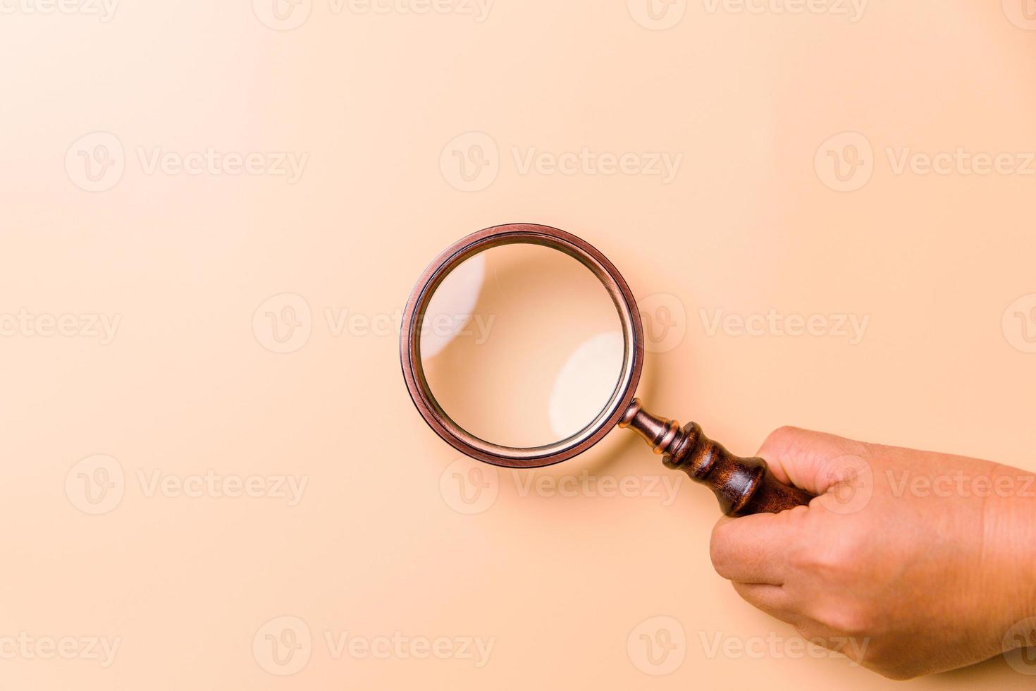 Magnifying glass on orange background. Top view. Flat lay. Copy space. Minimal creative concept. Blue background in pastel colours photo