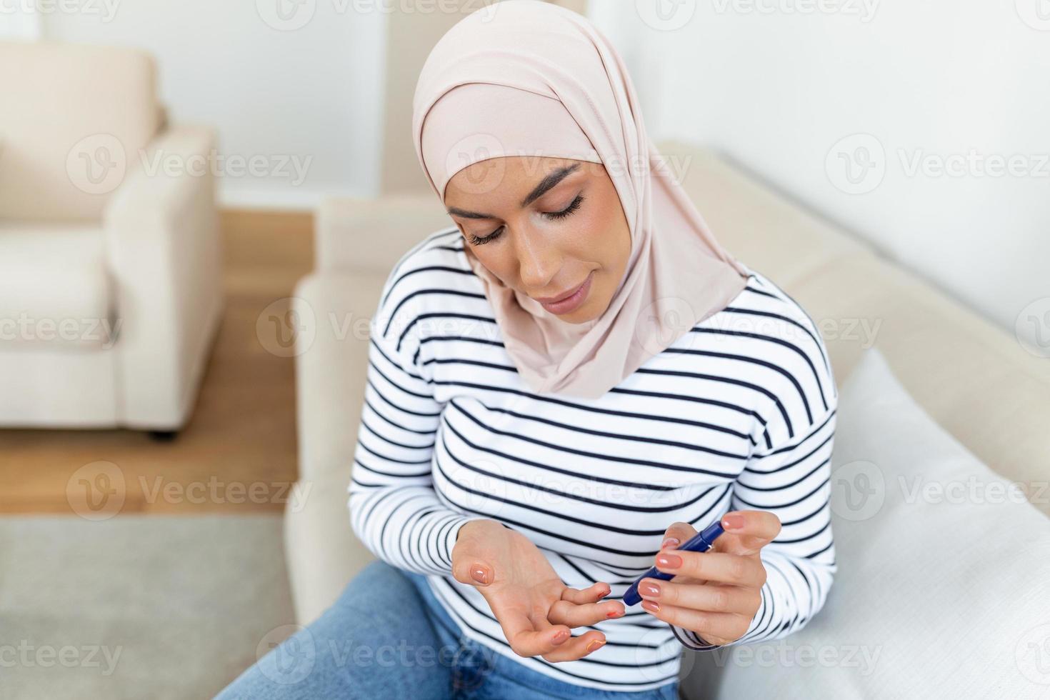 Young Arabic Muslim woman measures blood sugar level. Diabetes using glucometer. photo