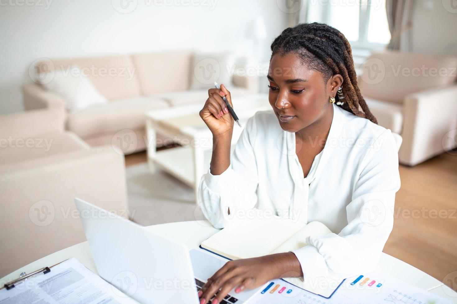 Serious frowning African American ethnicity woman sit at workplace desk looks at laptop screen read e-mail feels concerned. Bored unmotivated tired employee, problems difficulties with app photo