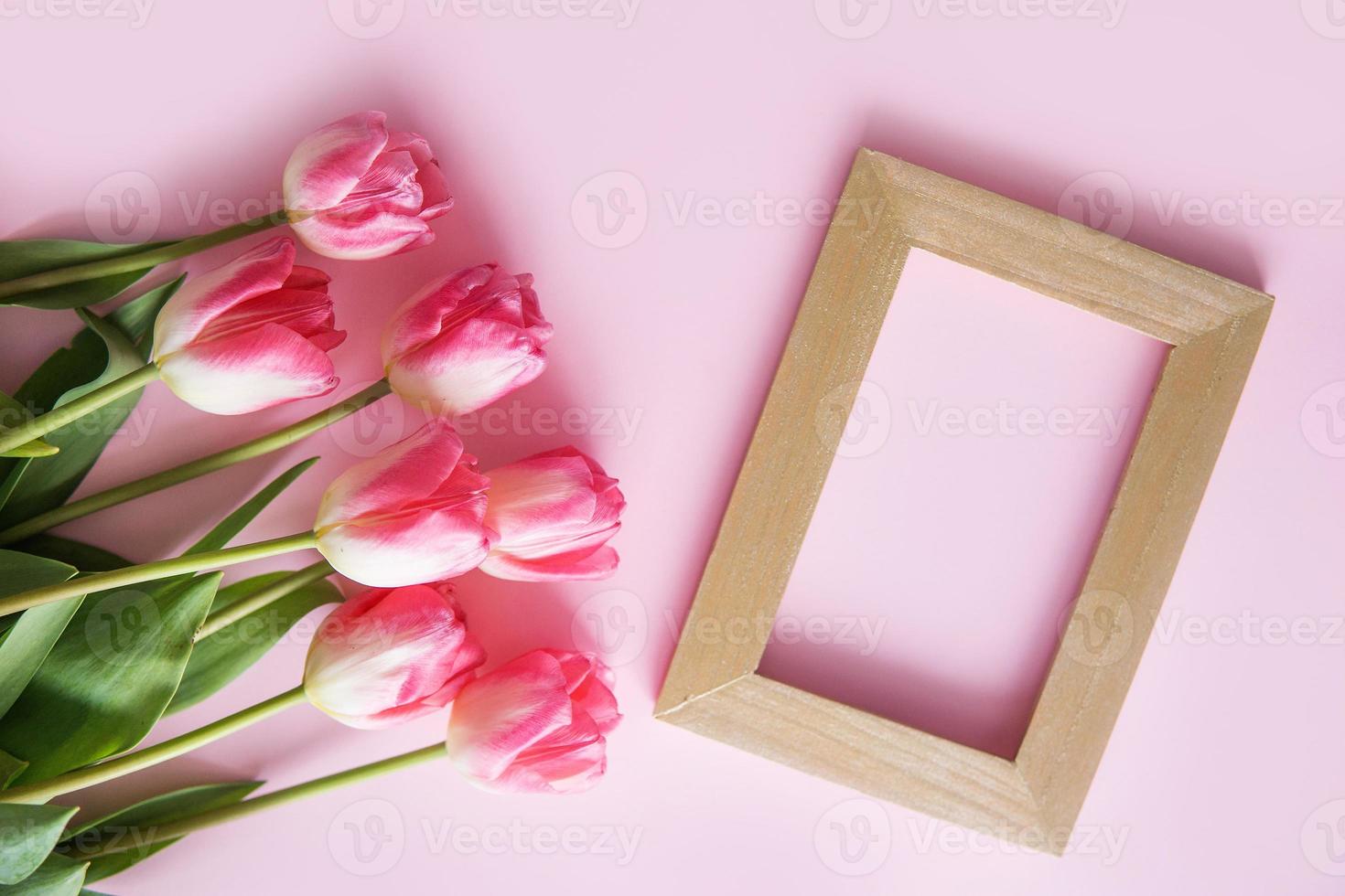 Pink Tulip flowers are arranged on a pink background. The view from the top, flat lay. Empty space for the text. Spring concept. Women's day. Mother's day. photo