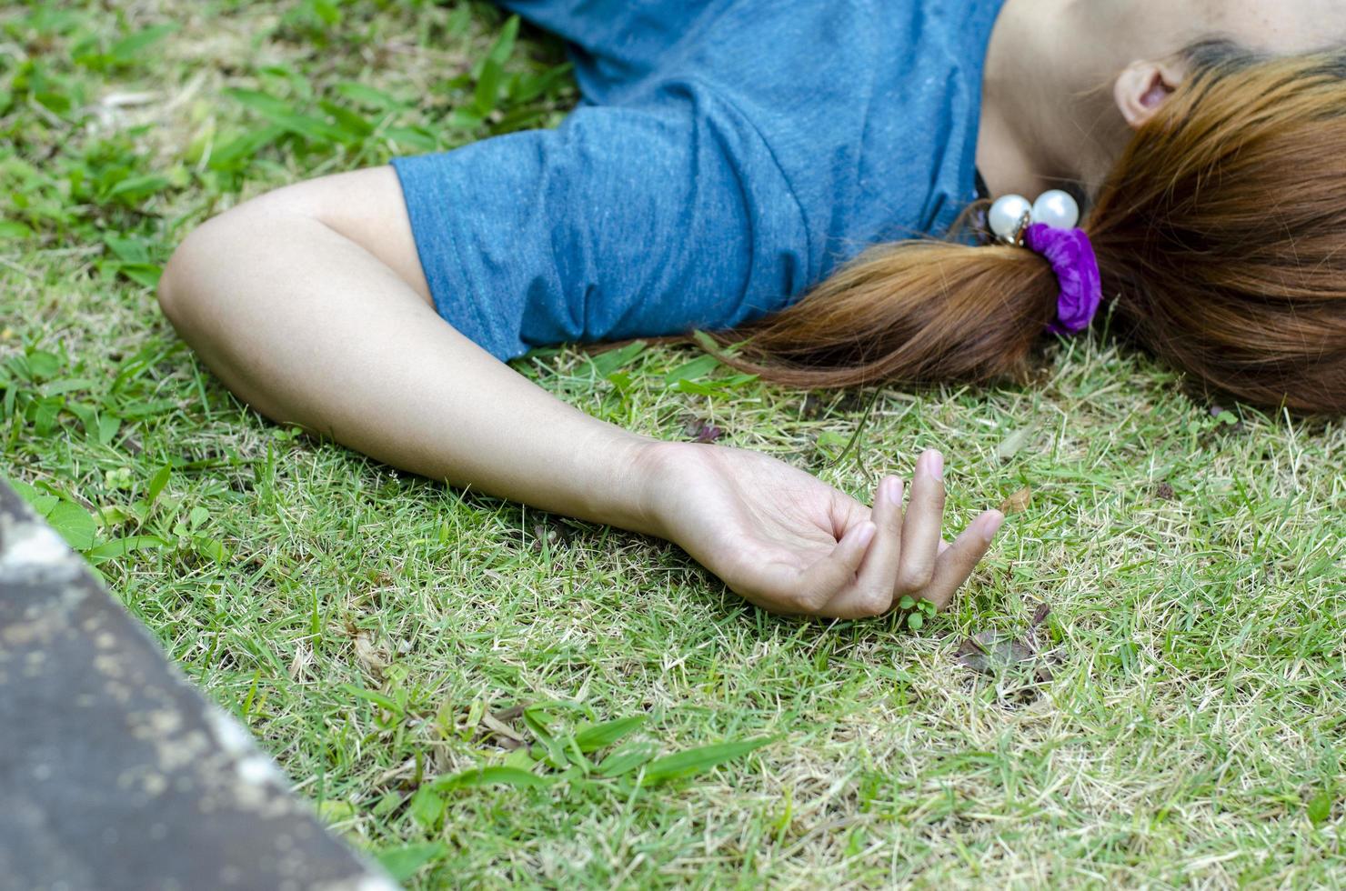 Young Asian woman fainting on grass in park in summer because outdoors of hot weather photo