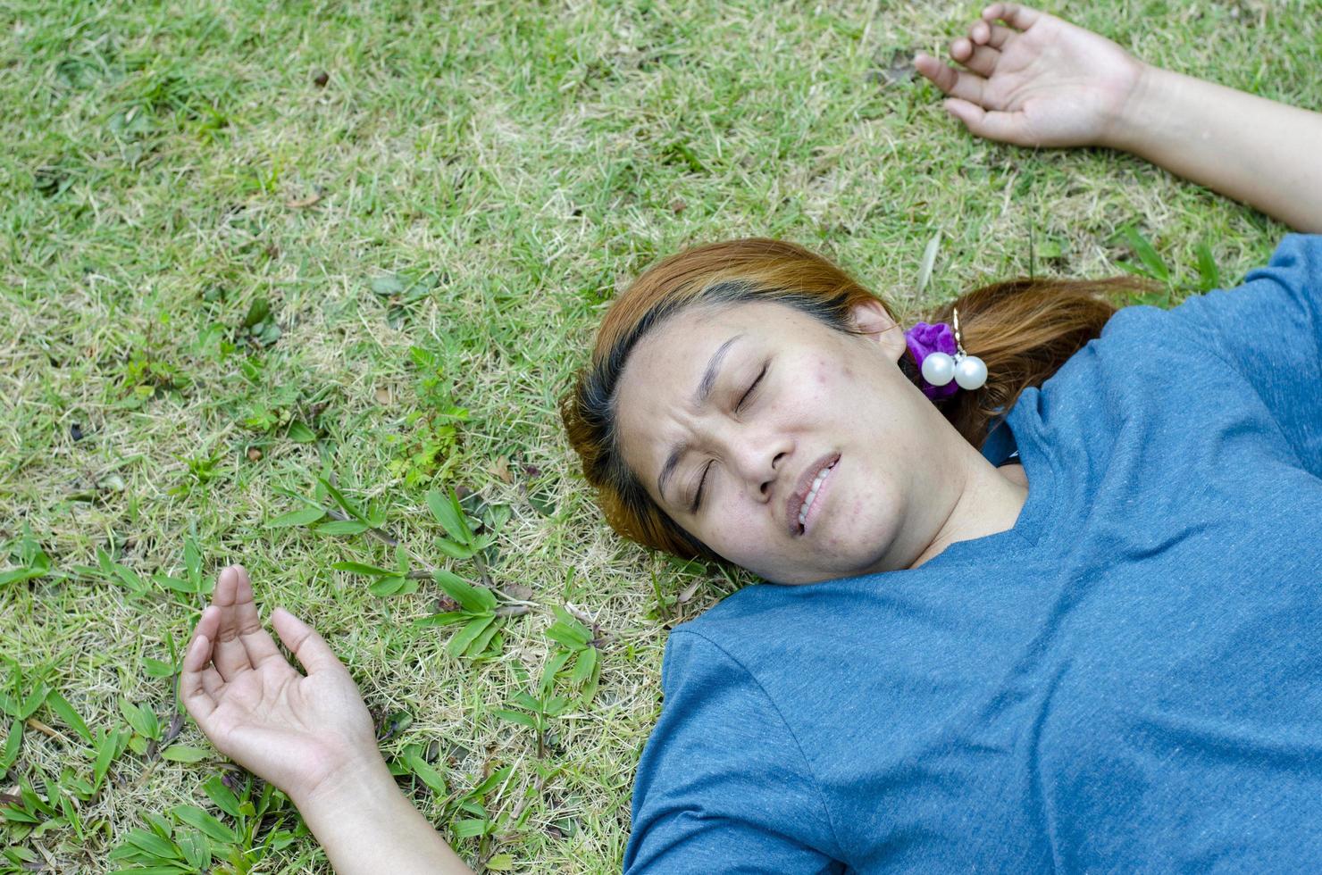 Young Asian woman fainting on grass in park because outdoors of hot weather photo