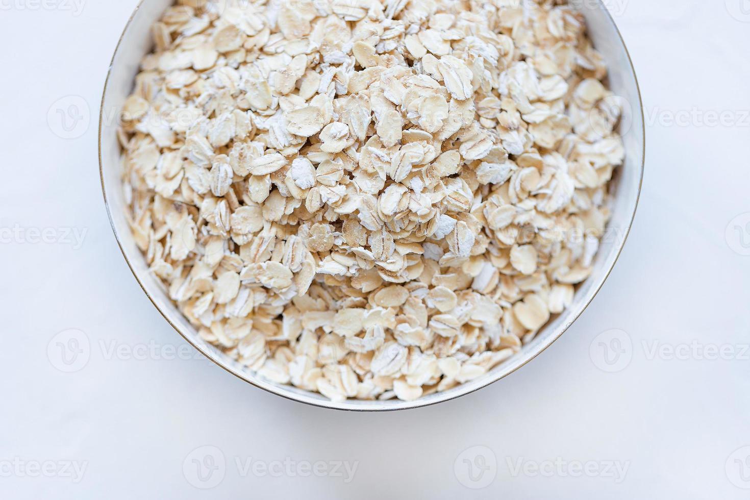 Uncooked oatmeal or oat flakes in a bowl photo