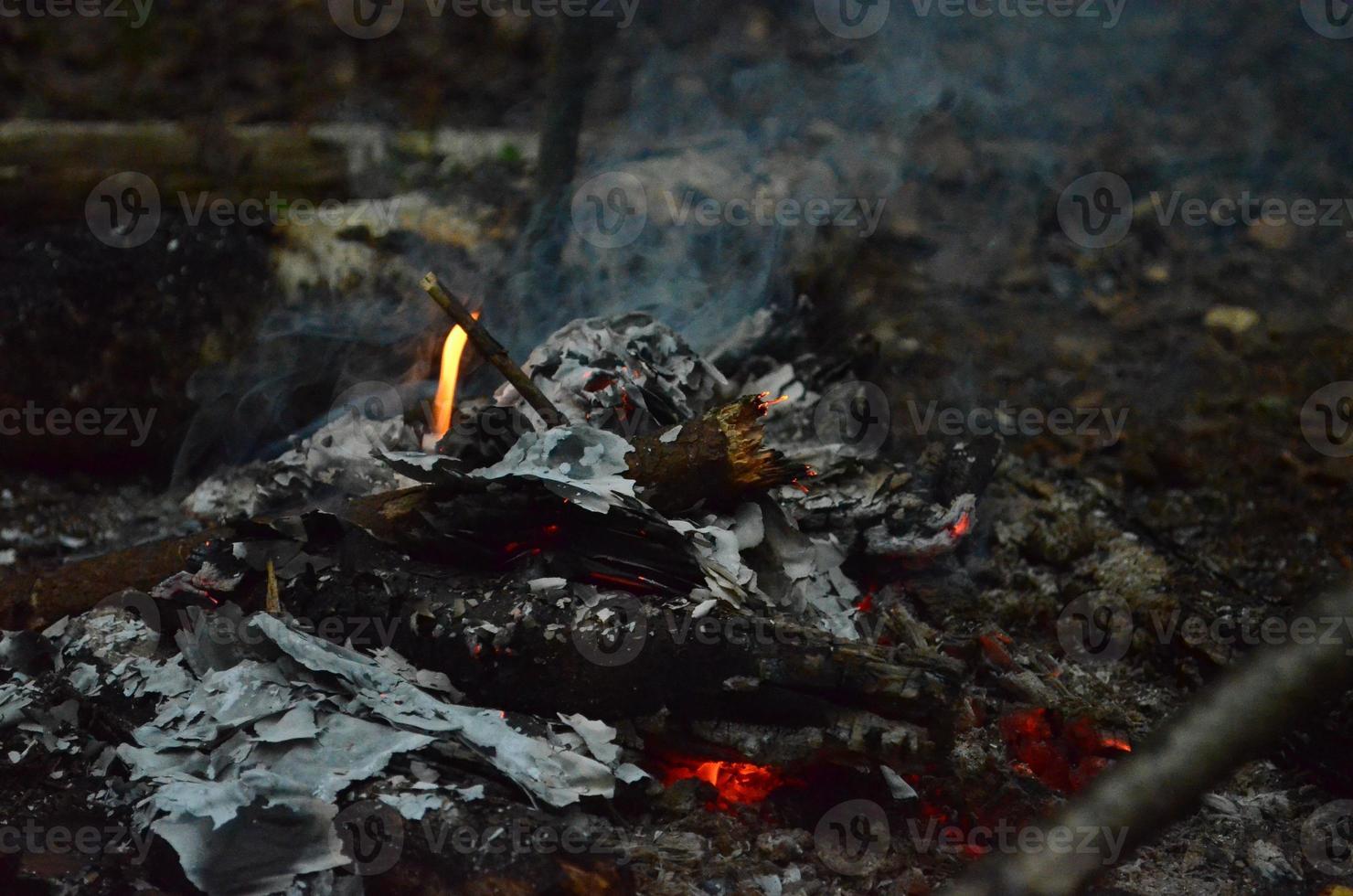 Glowing embers in hot red color. The hot embers of burning wood log fire. Firewood burning on grill. Texture bonfire embers. Gray and red embers abstract background. photo