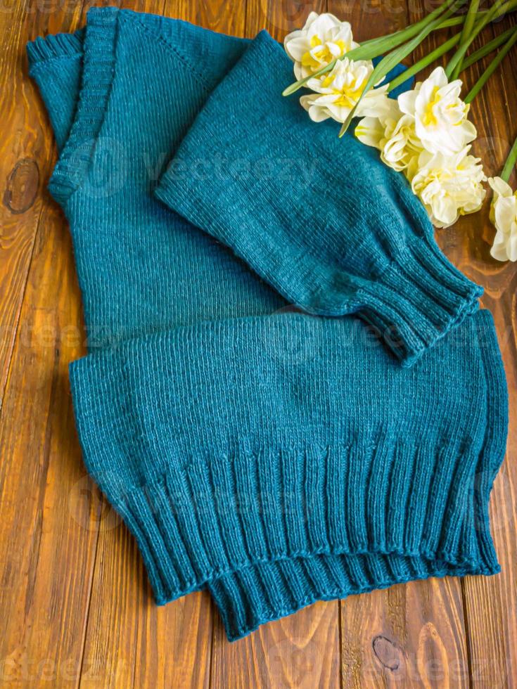 Knitted handmade products. Knitted fabric of colored threads in the color of petrol. Brown background. photo