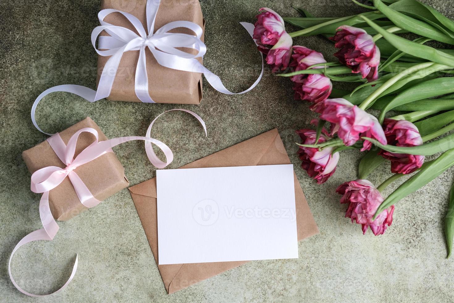 A bouquet of tulips, gifts and mock up blank white paper card for text. Flat lay, top view. Place for text. Greeting card photo