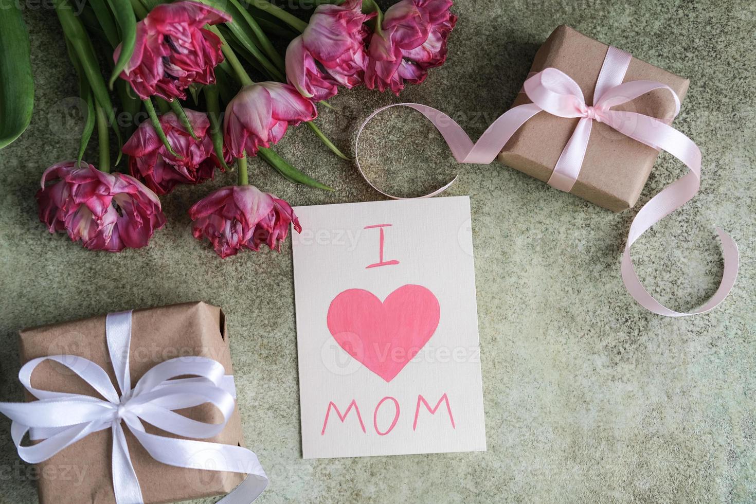 A bouquet of tulips, gifts and a card with the text I love mom on a tray. Mother's day concept photo