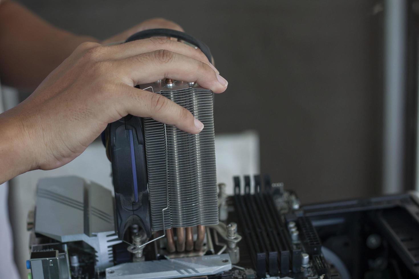 The hand of the technician is holding heat sink to repair the computer. photo