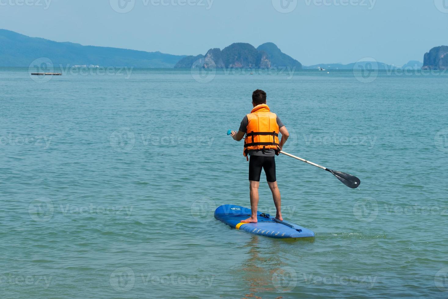 Asian man Playing SUP Board in Blue Sea in Summer Vacation photo