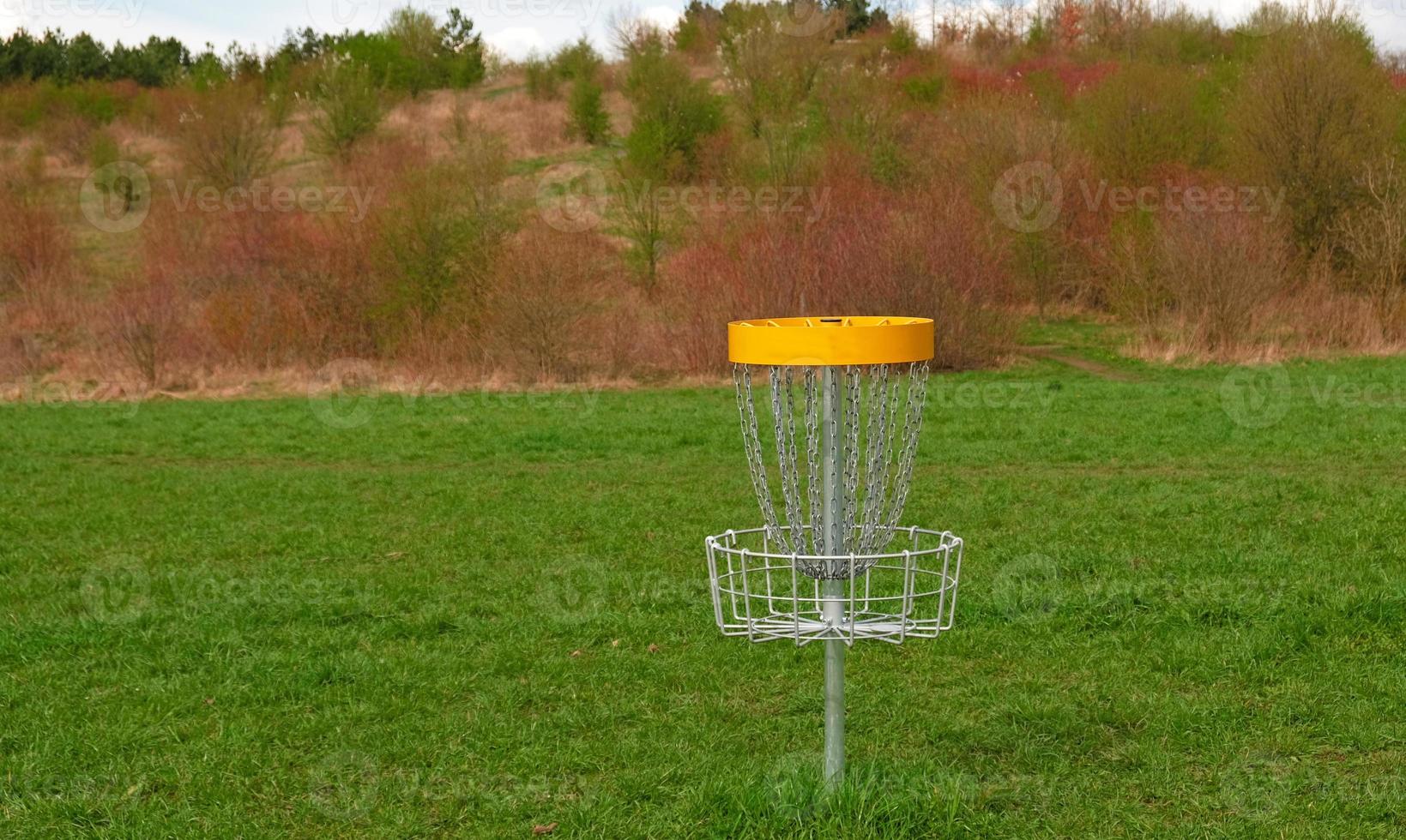 Disc Golf basket. Frisbee golf is sport and hobbie in outdoor park. Metal basket with chains for disc game surrounded by vibrant green trees. photo