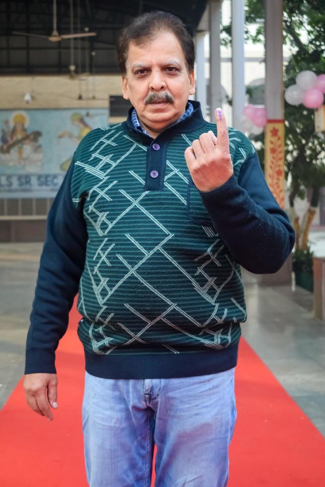 New Delhi, India - April 04 2023 - Unidentified people showing their ink-marked fingers after casting votes in front of polling booth of east Delhi area for MCD local body Elections 2022 photo