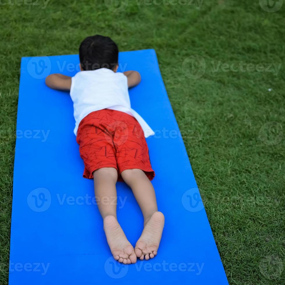 Asian smart kid doing yoga pose in the society park outdoor, Children's yoga pose. The little boy doing Yoga exercise. photo