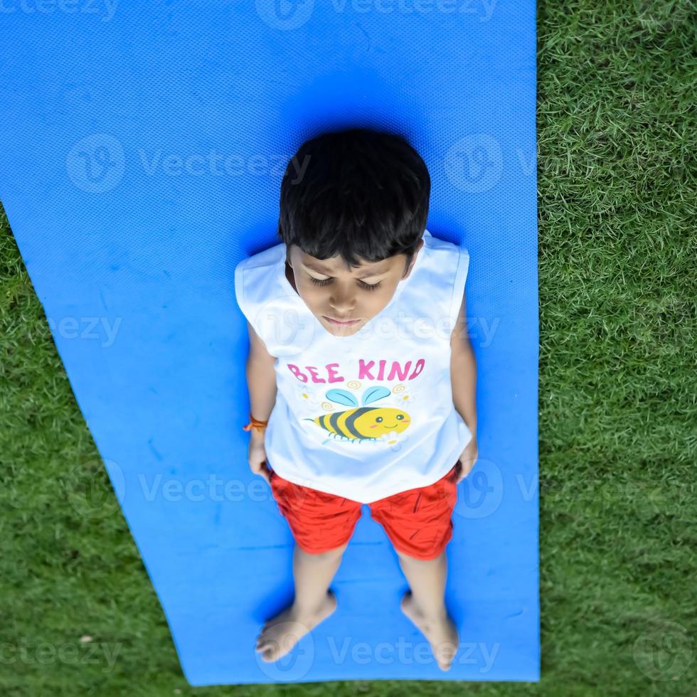 Asian smart kid doing yoga pose in the society park outdoor, Children's yoga pose. The little boy doing Yoga exercise. photo