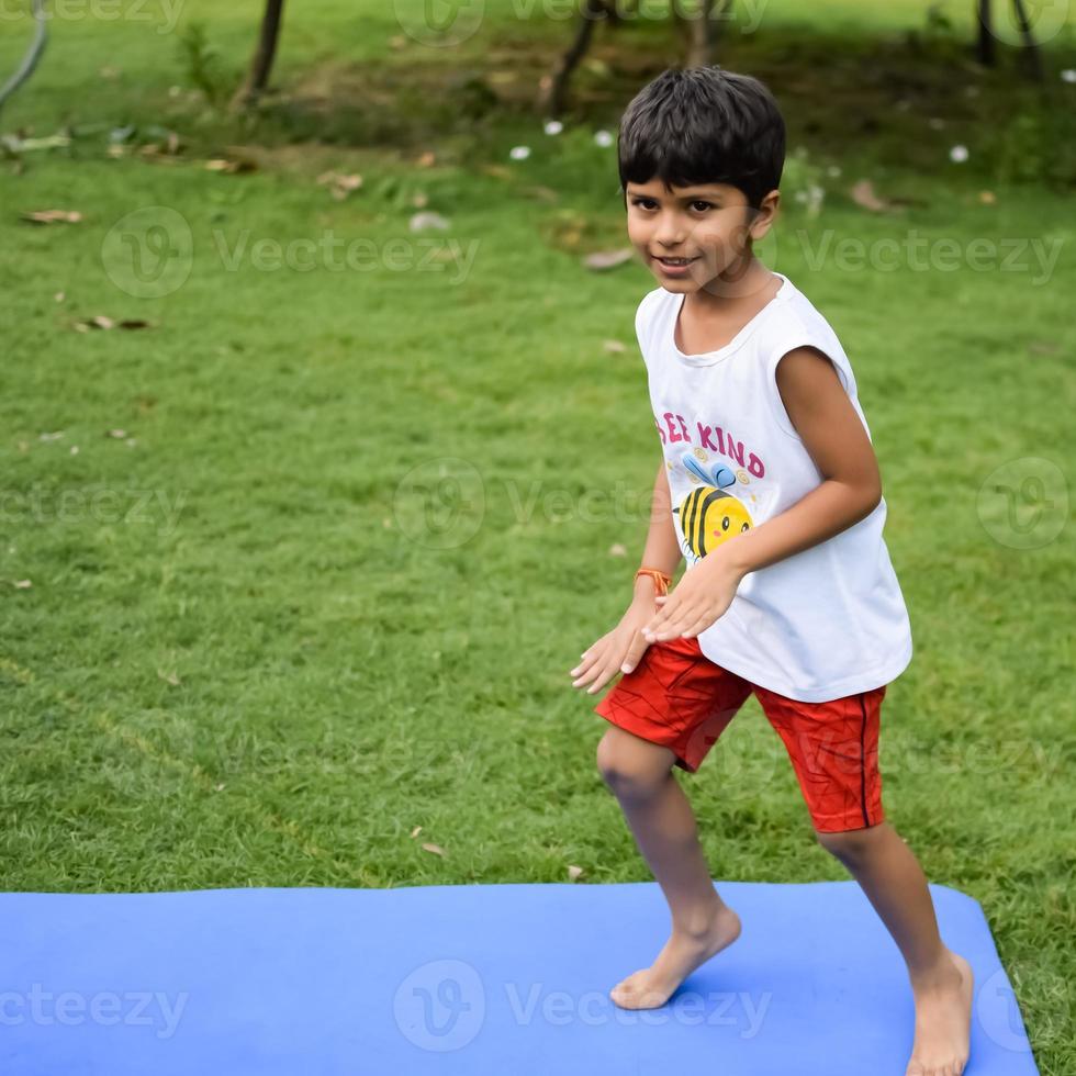 Asian smart kid doing yoga pose in the society park outdoor, Children's yoga pose. The little boy doing Yoga exercise. photo