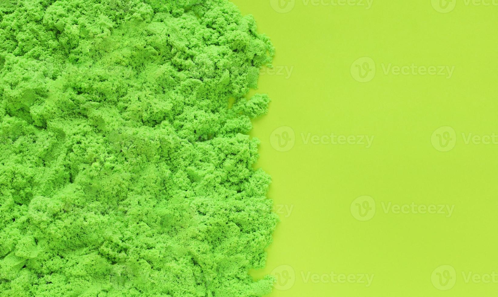 Green kinetic sand on light green paper background with copy space. Kids sensory game, development concept. Early sensory education for children. Leisure time on holidays. photo