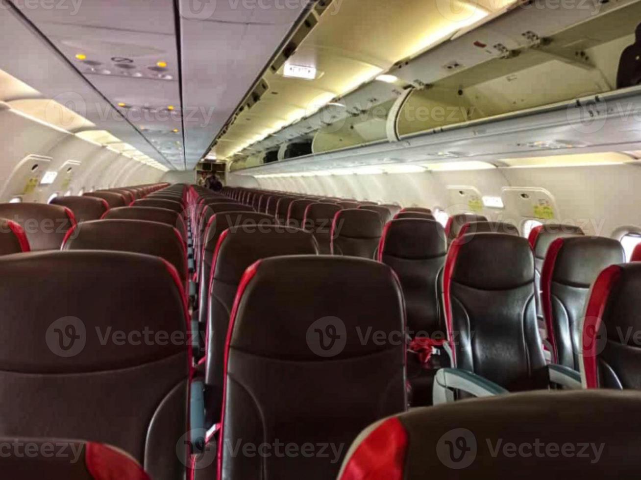 Empty comfortable black and red seats with seatbelts in modern aircraft cabin during flight at daytime photo