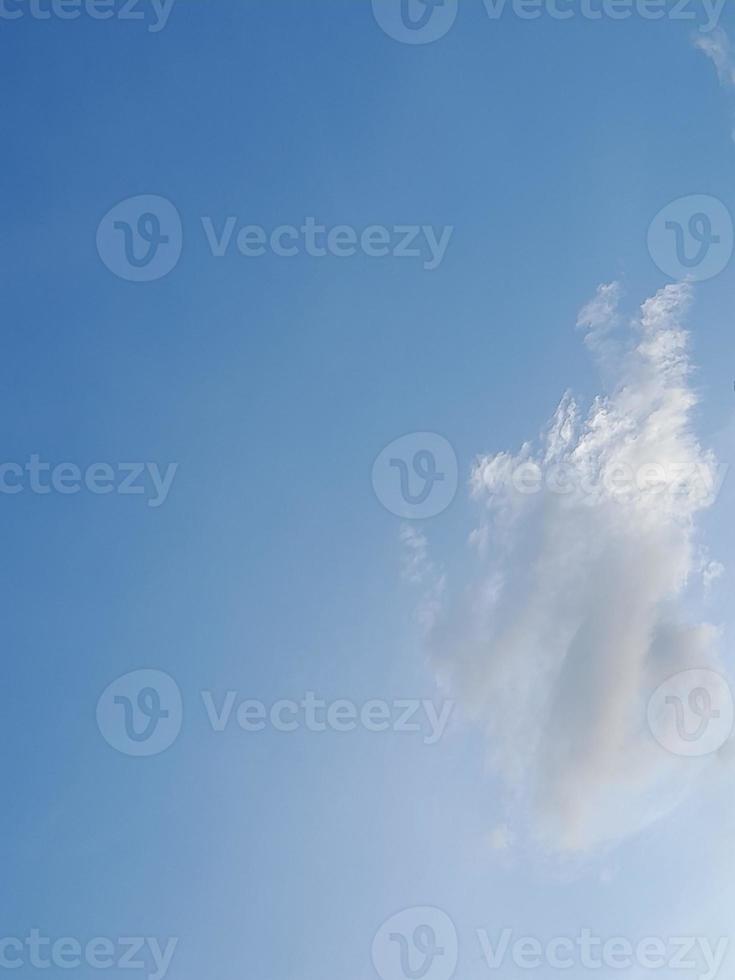 White clouds in the blue sky. Beautiful bright blue background. Light cloudy, good weather. Curly clouds on a sunny day. photo