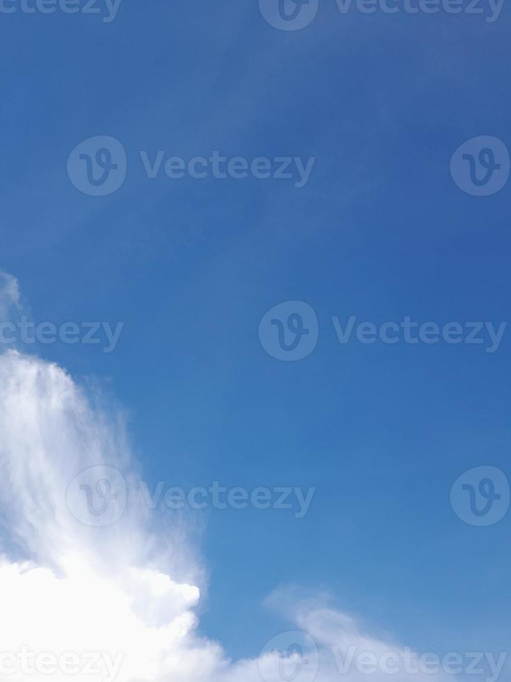 White clouds in the blue sky. Beautiful bright blue background. Light cloudy, good weather. Curly clouds on a sunny day. photo