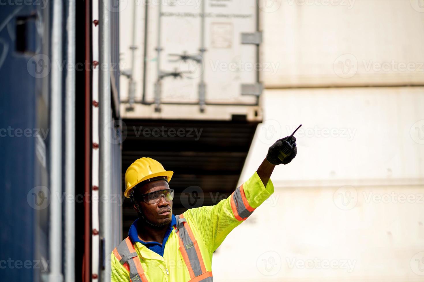 Worker man in protective safety jumpsuit uniform with yellow hardhat and use  Walkie Talkie check container at cargo shipping warehouse. transportation import,export logistic industrial service photo