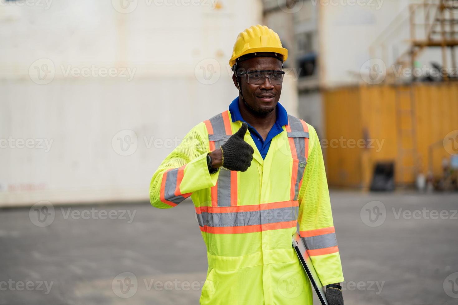 Worker man in protective safety jumpsuit uniform with yellow hardhat.Worker in factory showing thumbs up photo